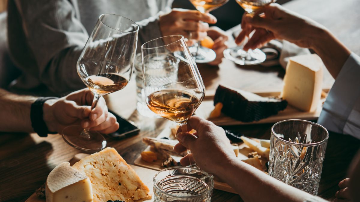 people swirling wine in a glass over a table with cheese boards