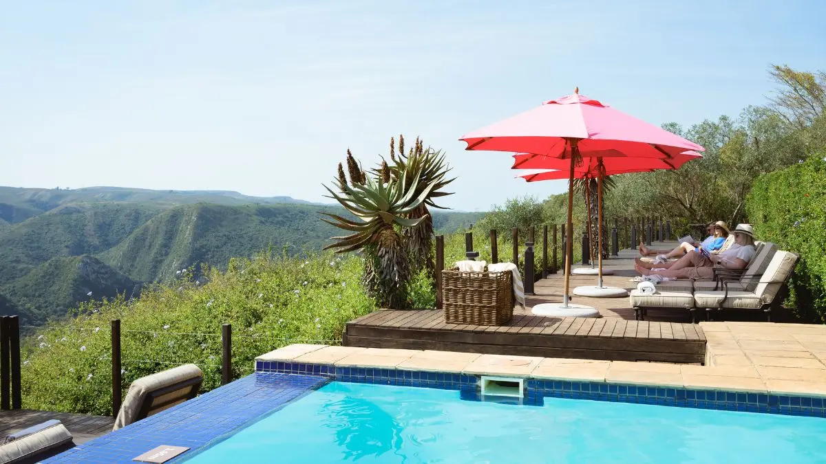 an infinity swimming pool with a deck and pink umbrellas