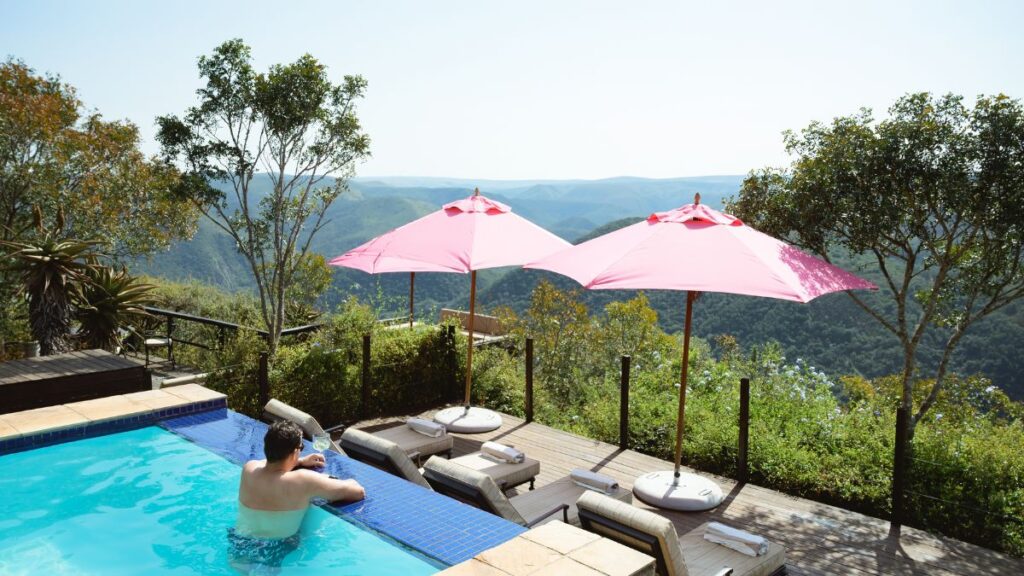 a person enjoying the view from camp figtree luxury safari lodge swimming pool