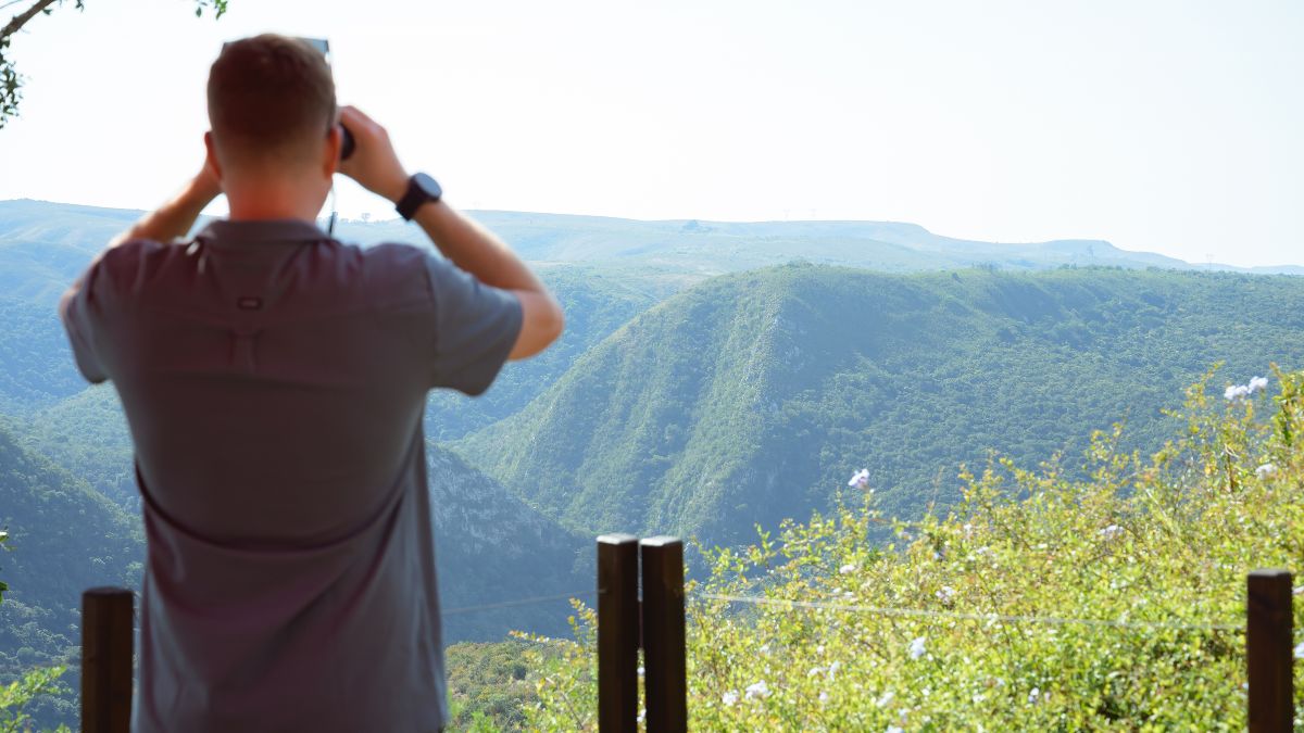 person looking at a mountain view through binoculars