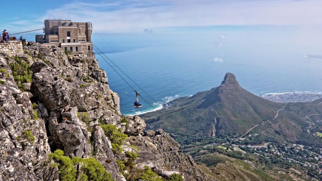 a cable car going up a mountain with the ocean in the background